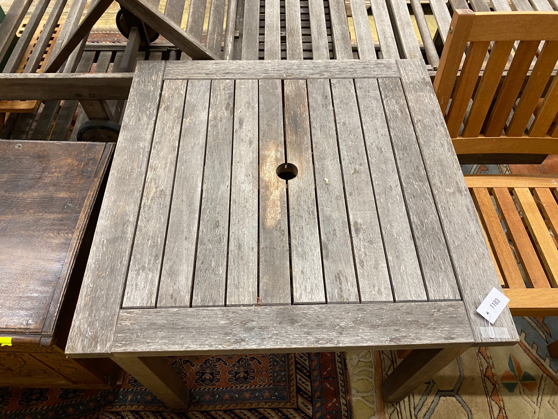 A weathered teak square garden table, width 80cm, height 73cm together with two teak elbow chairs